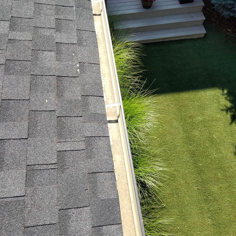Gutter system with asphalt shingle roof and yard view Gutter system with asphalt shingle roof and yard view