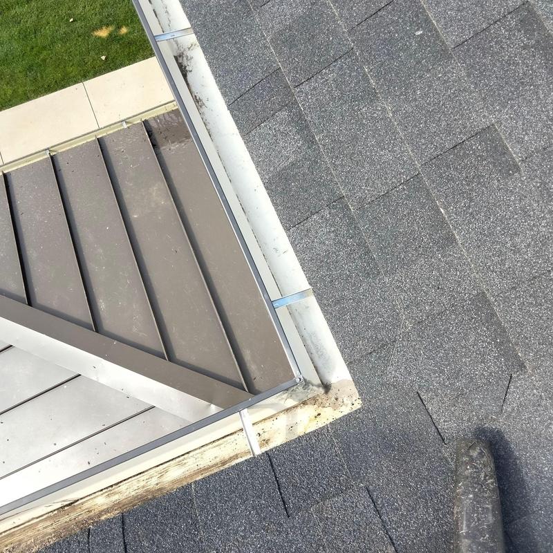 Gutter with minor debris near roof shingles and metal flashing Gutter with minor debris near roof shingles and metal flashing