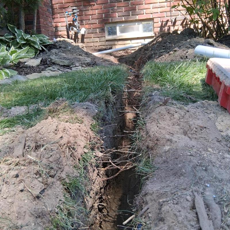 Sump pump discharge line trench excavation near house