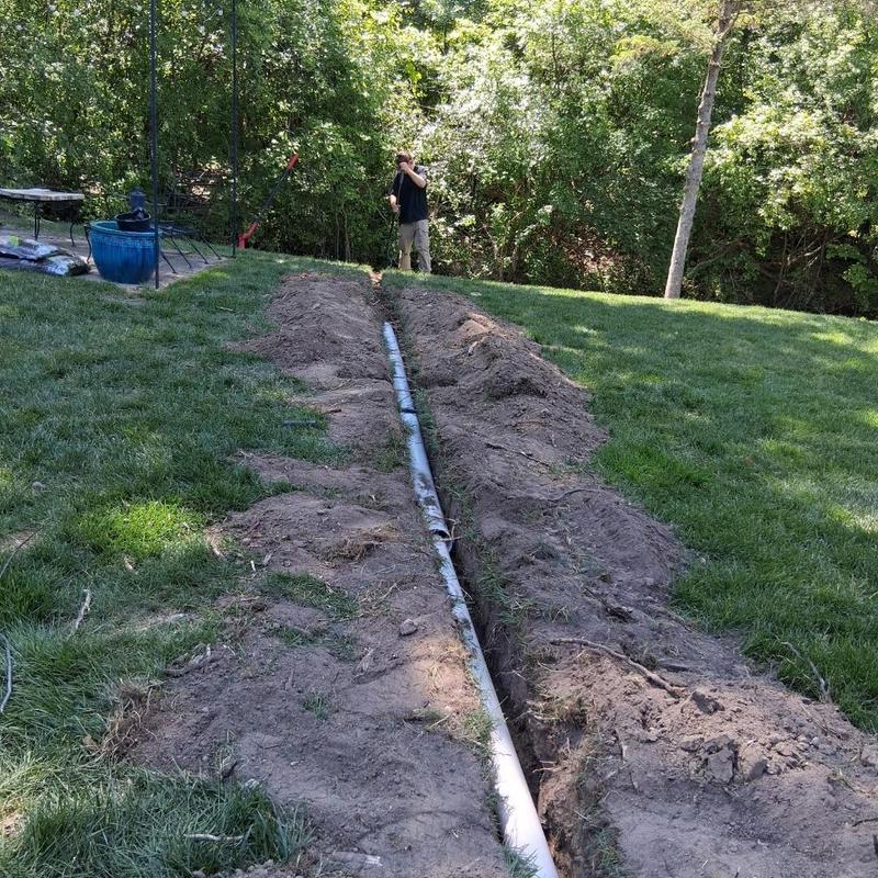 Sump pump discharge line installation in yard trench