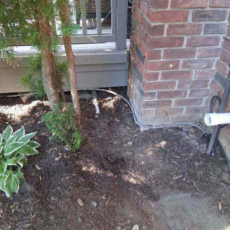 Sump pump discharge line installation near brick wall