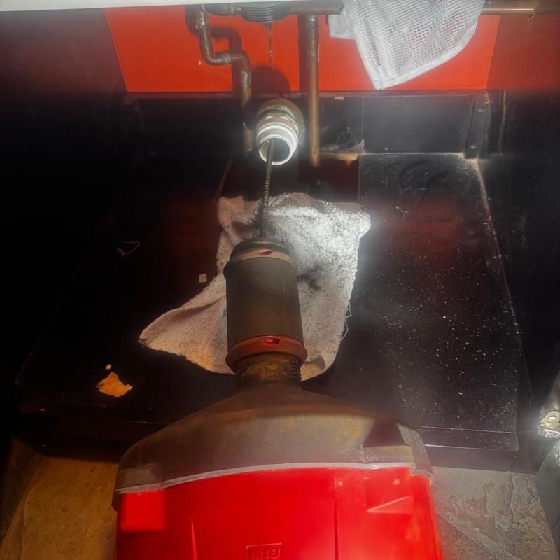 Laundry drain line clog clearing with plumber's snake tool