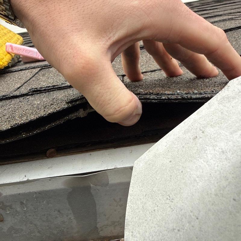 Asphalt shingles lifted to show roofing damage and flashing
