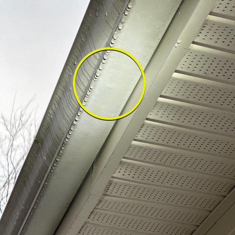 Metal gutter section with dent circled in yellow