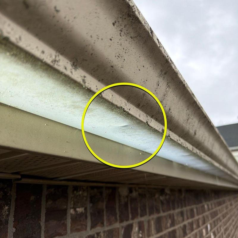 Gutter dent and grime buildup on house exterior