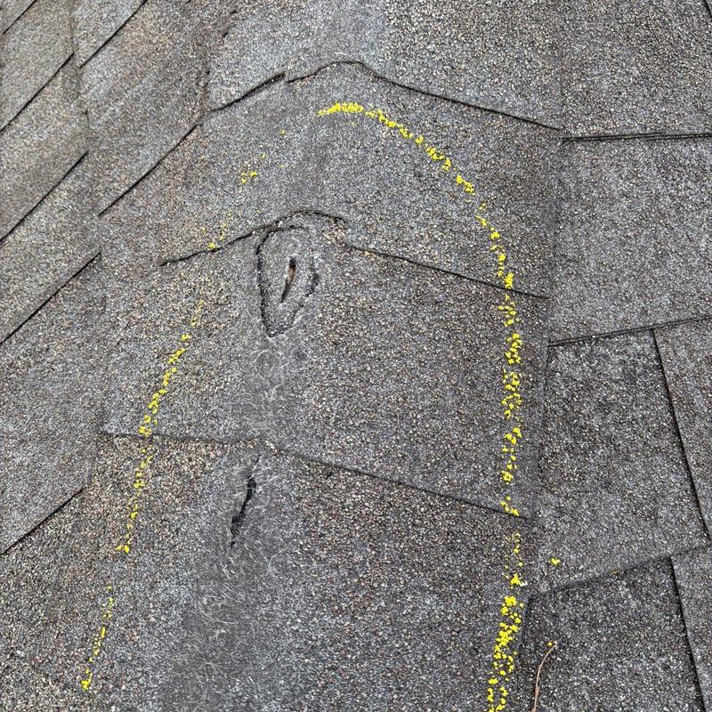 Shingle damage with yellow marking on roof surface