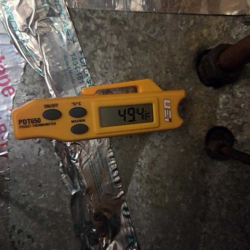 Pocket thermometer showing 49.4°F on HVAC unit surface Pocket thermometer showing 49.4°F on HVAC unit surface