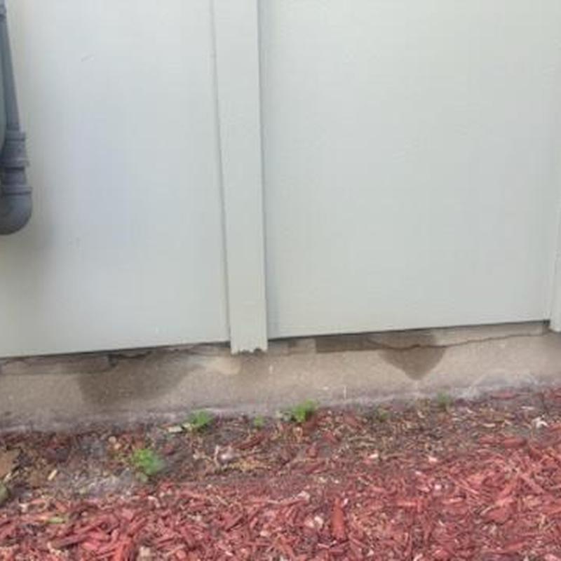 Fence base moisture stains near ground with mulch nearby Fence base moisture stains near ground with mulch nearby