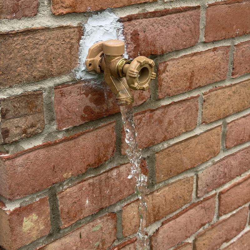 Frost proof outdoor faucet with running water on brick wall Frost proof outdoor faucet with running water on brick wall