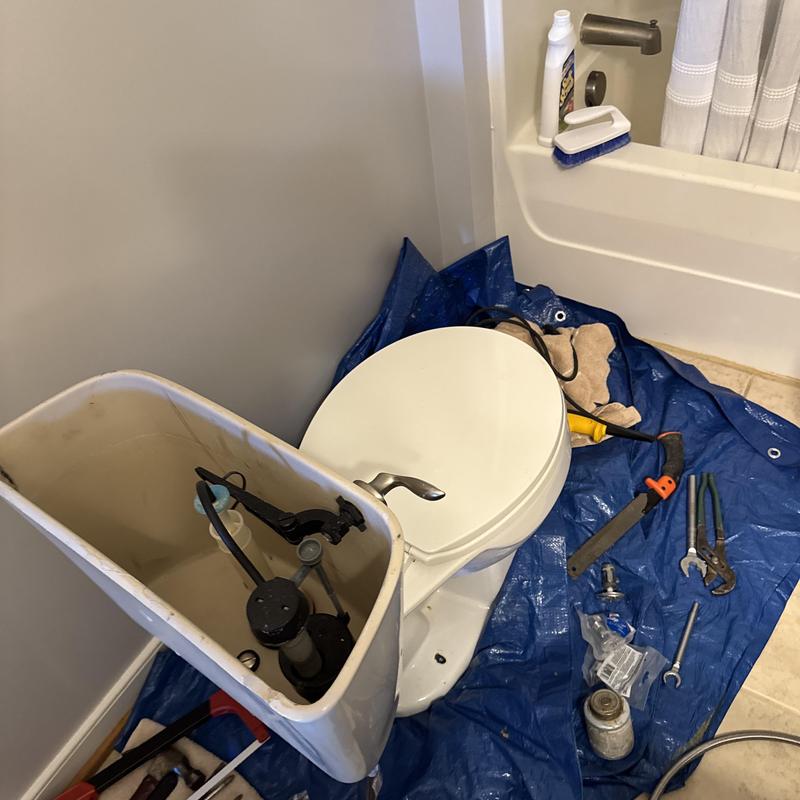 Toilet tank with tools on protective tarp during repair Toilet tank with tools on protective tarp during repair