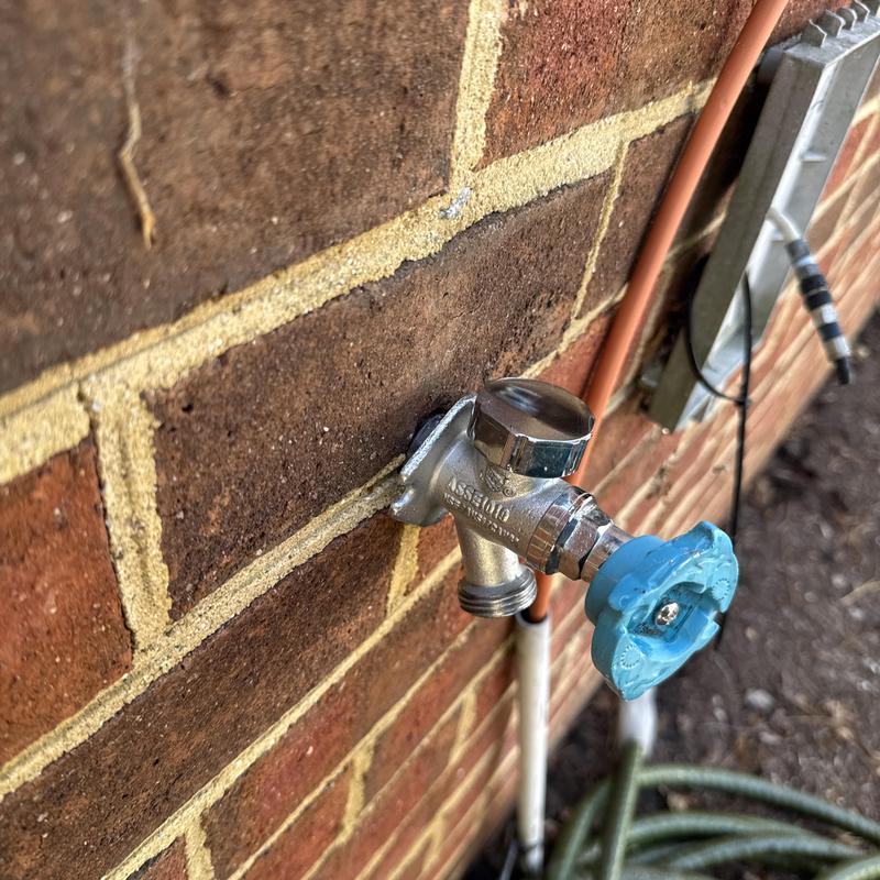 Frost proof hose bib with blue handle valve on brick wall Frost proof hose bib with blue handle valve on brick wall