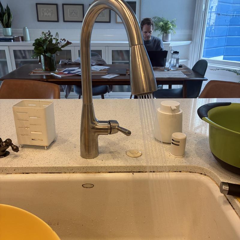 Kitchen faucet with water flowing in residential sink