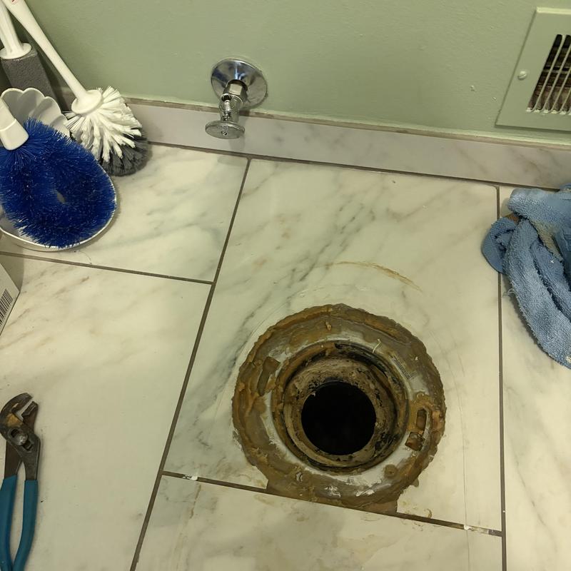 Toilet flange with removed toilet and plumbing tools nearby Toilet flange with removed toilet and plumbing tools nearby
