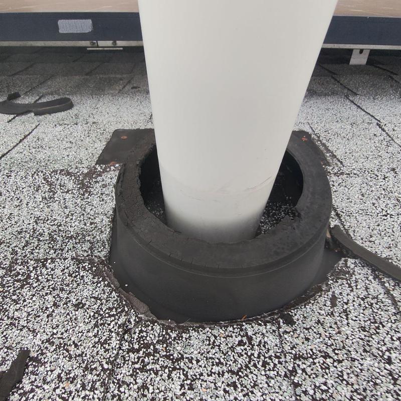Pipe flashing with cracked seal on roof surface