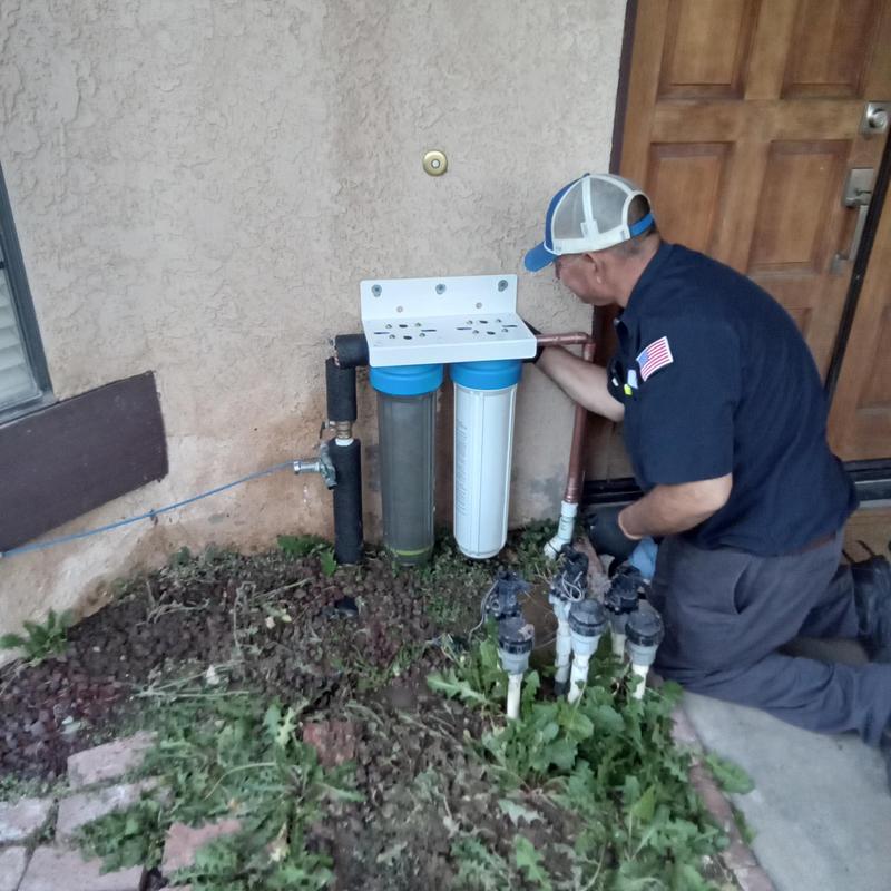 Water treatment filter replacement outdoors by plumber