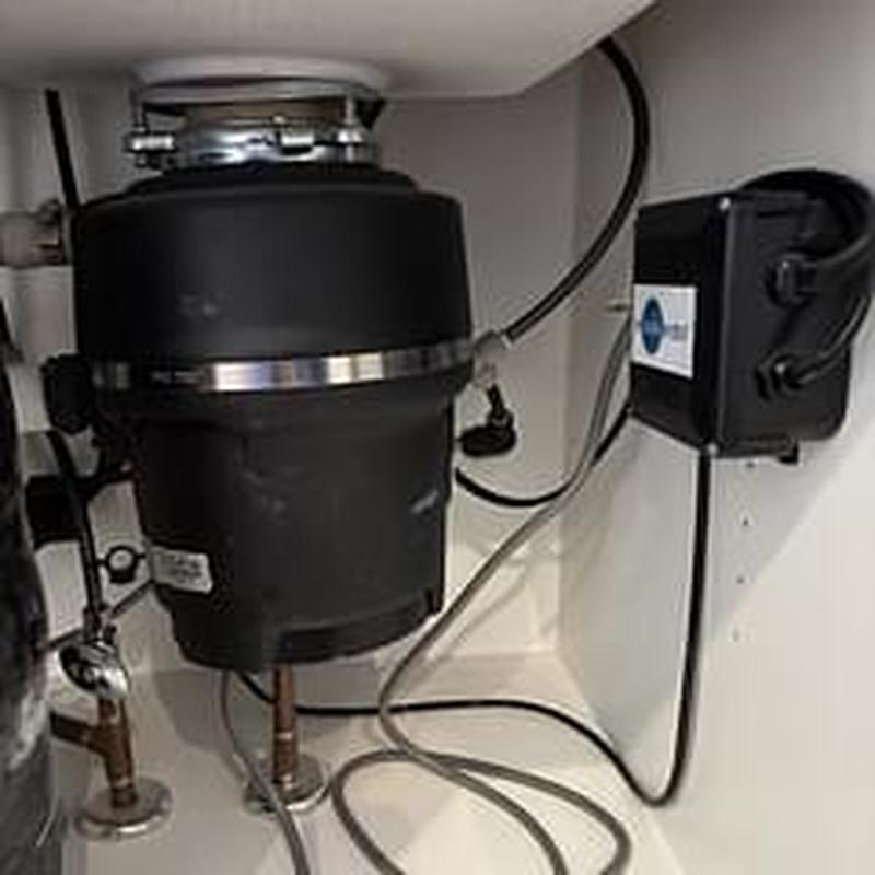Garbage disposer under kitchen sink with wiring and pipes Garbage disposer under kitchen sink with wiring and pipes