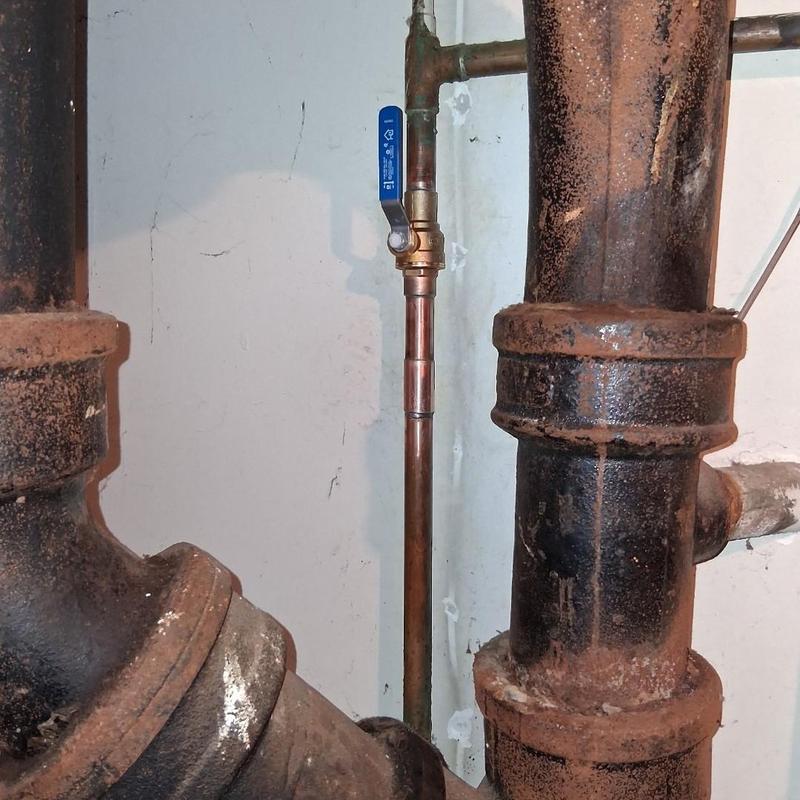 Copper water pipe with valve among old cast iron pipes