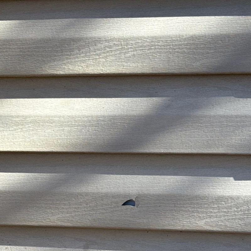 Vinyl siding with visible puncture hole damage