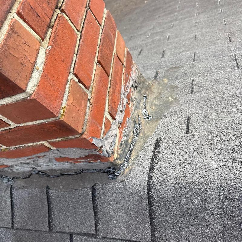 Brick chimney flashing with sealant on shingle roof