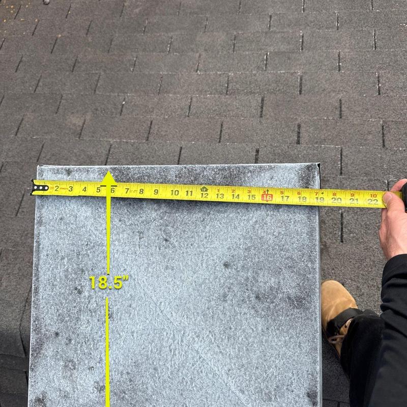 Metal roof flashing with measuring tape on shingles