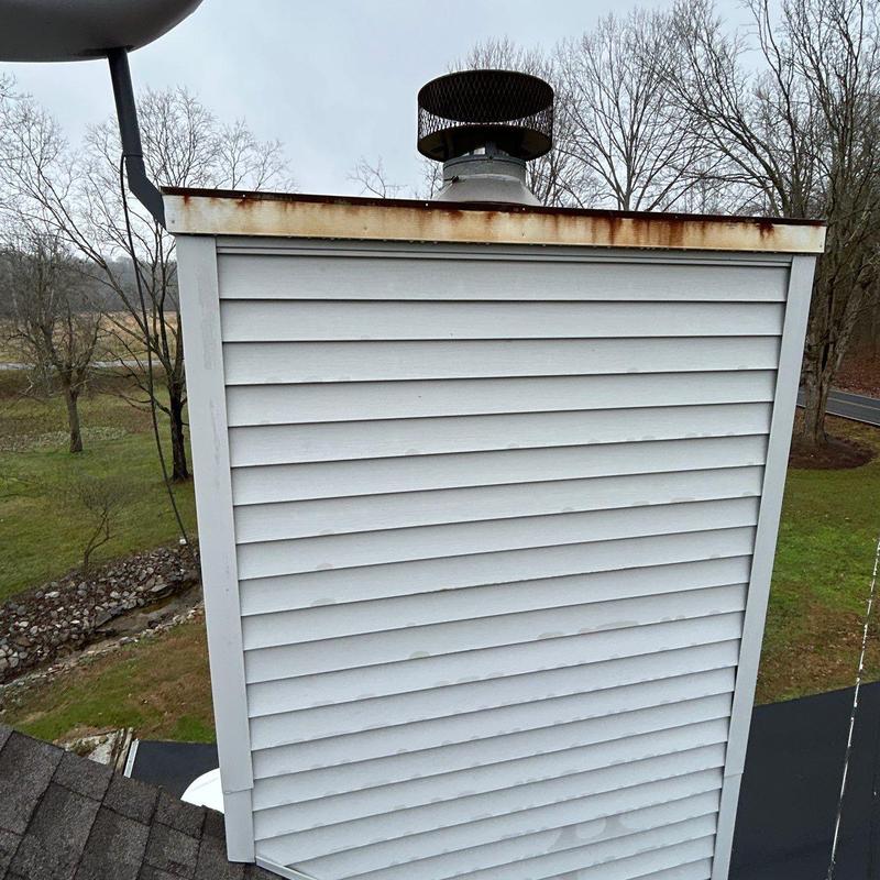 Metal chimney cap with rust and vent pipe on roof