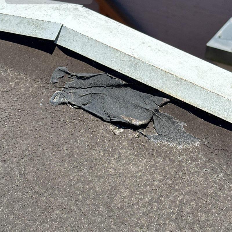 Flat roof membrane with cracking and damage near flashing