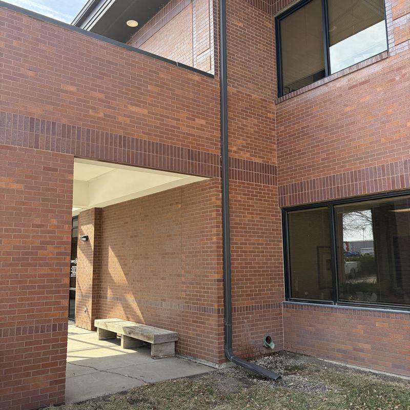 Downspout and brick building exterior with bench