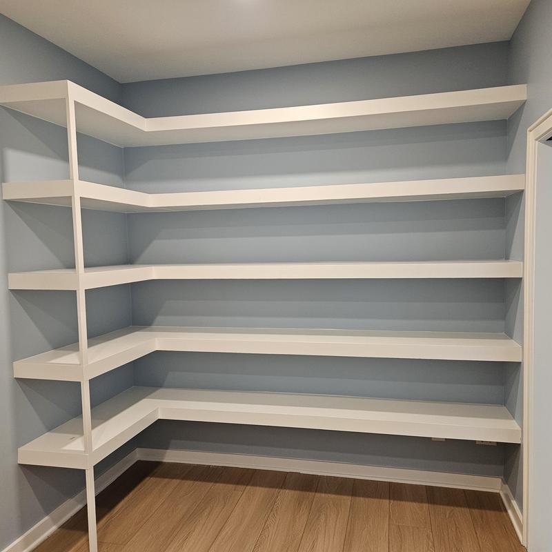 Corner wall-mounted white shelving unit in room Corner wall-mounted white shelving unit in room