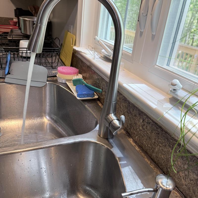 Kitchen faucet with running water over sink basin