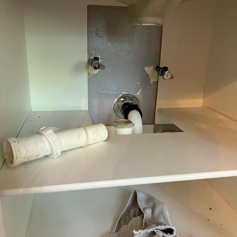 Bathroom sink drain pipe disassembled under vanity cabinet Bathroom sink drain pipe disassembled under vanity cabinet
