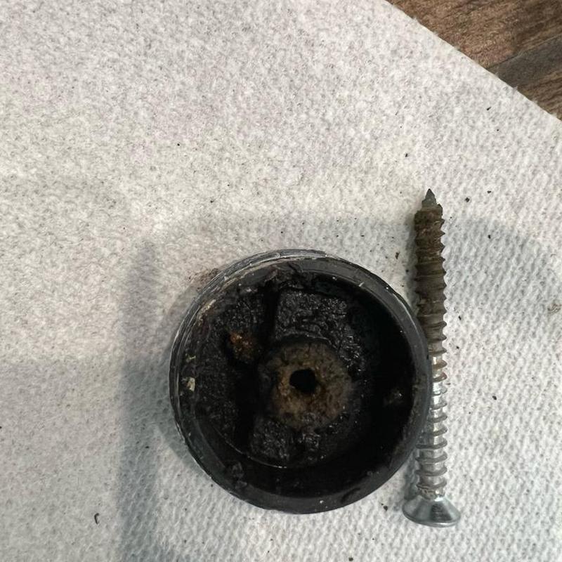 Rusty clean-out cap and screw removed from plumbing system Rusty clean-out cap and screw removed from plumbing system