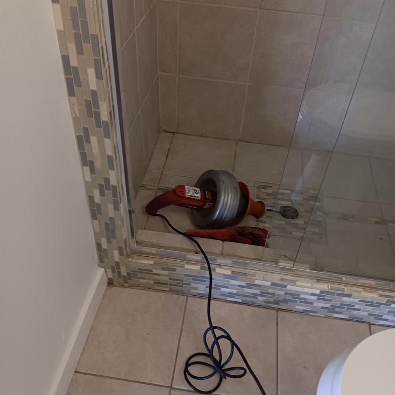 Shower drain snaking tool inside tiled shower stall