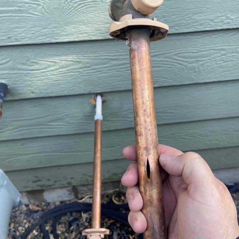 Copper pipe outside faucet with visible leak hole Copper pipe outside faucet with visible leak hole