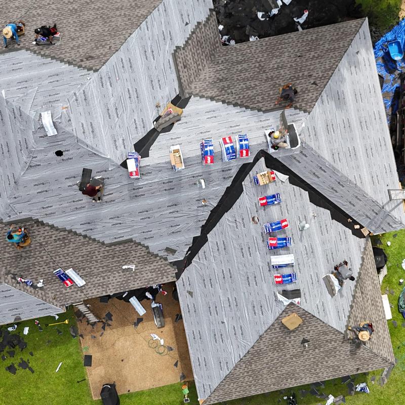 Roof underlayment installation with workers and materials