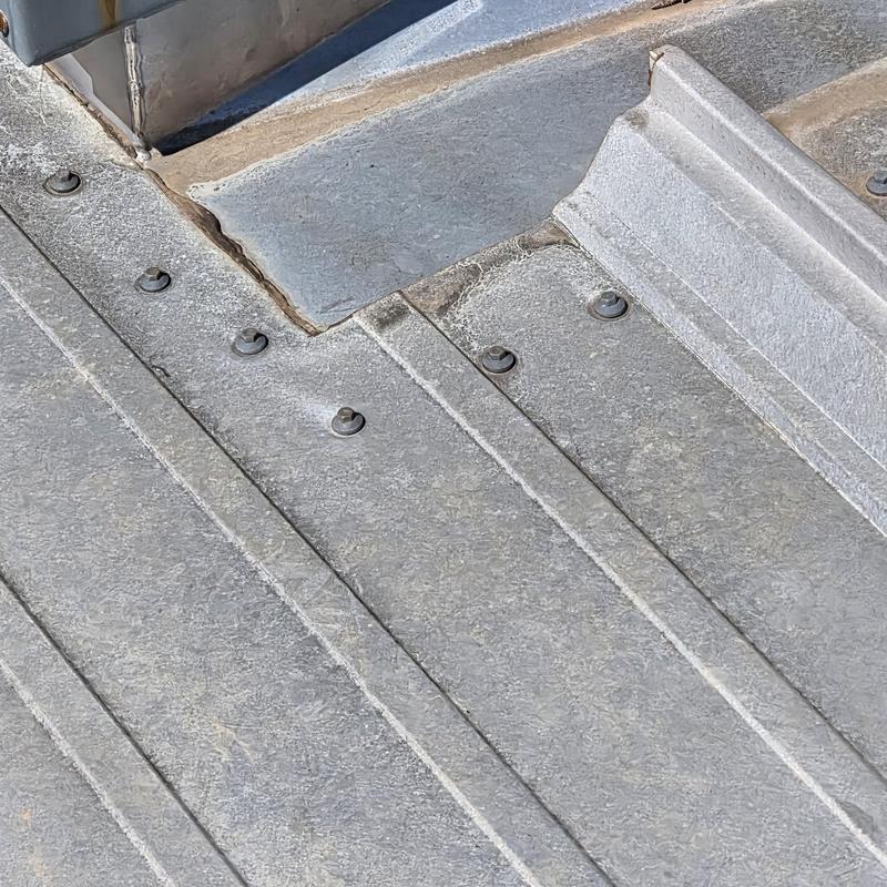 Metal roof base flashing near HVAC unit showing wear