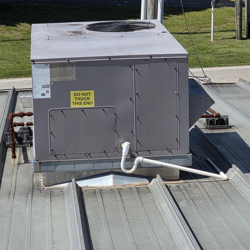 Rooftop HVAC unit base and drainage pipe on metal roof