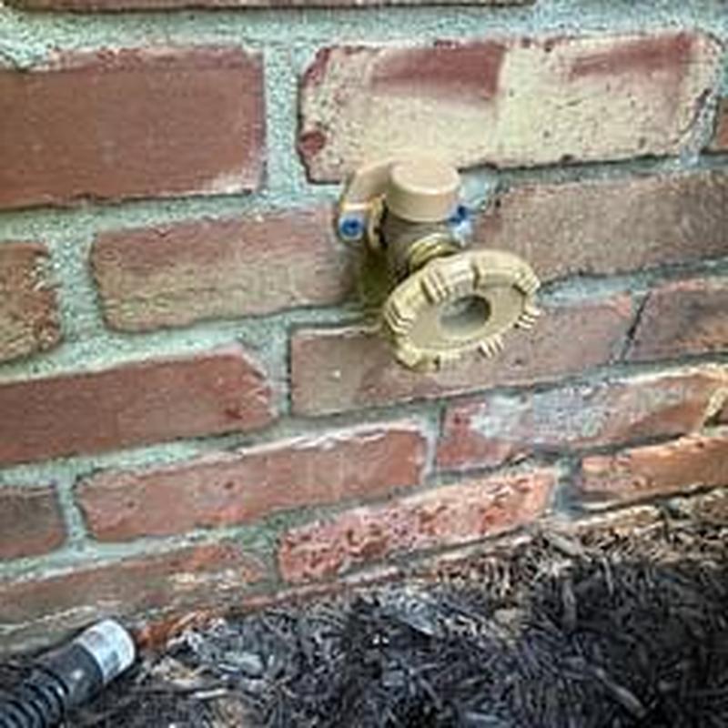 Hose bib valve on brick exterior wall with mulch base Hose bib valve on brick exterior wall with mulch base