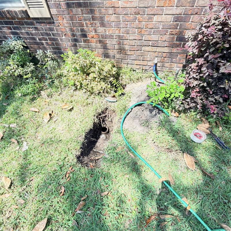 Sewer cleanout excavation near home wall with hose