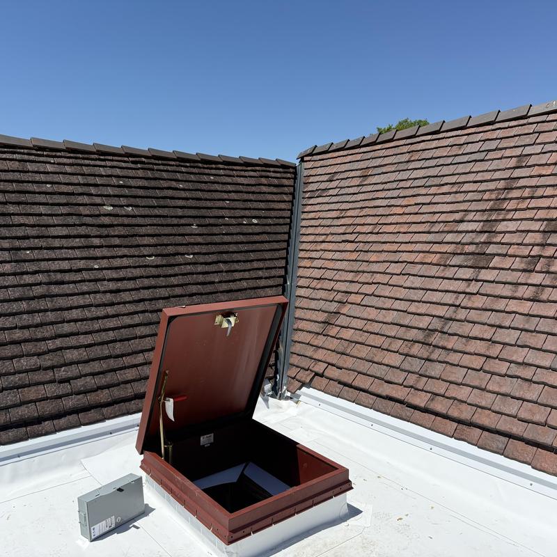 Clay tile roofing and open roof hatch on TPO membrane