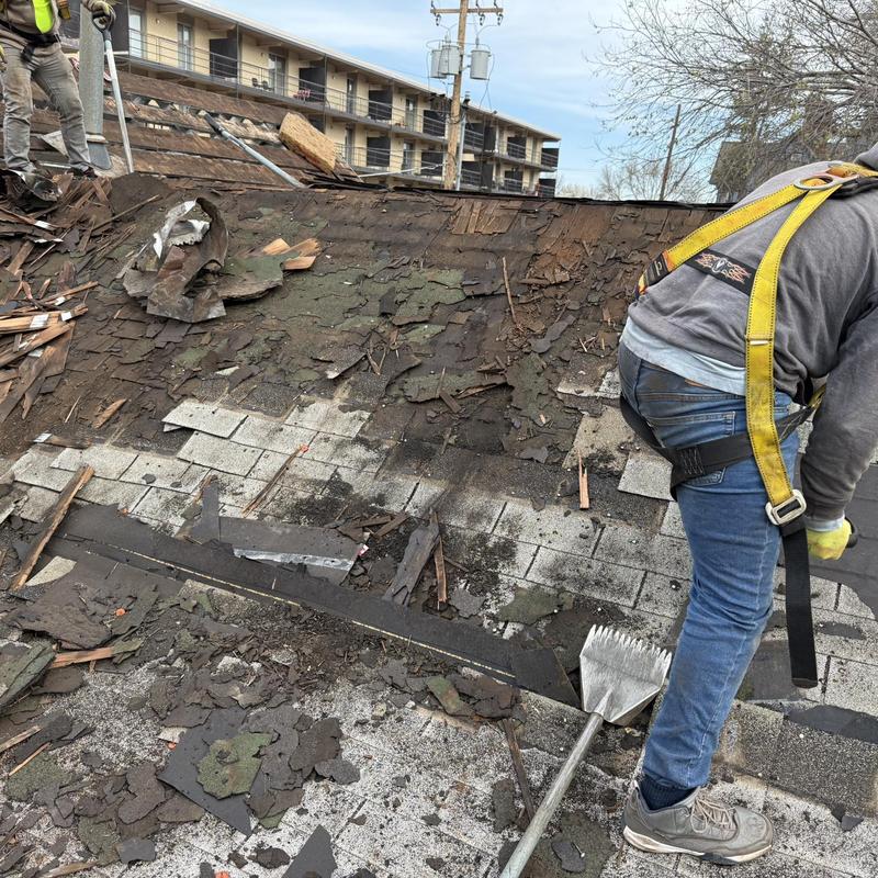 Roof shingles removal with worker in safety harness