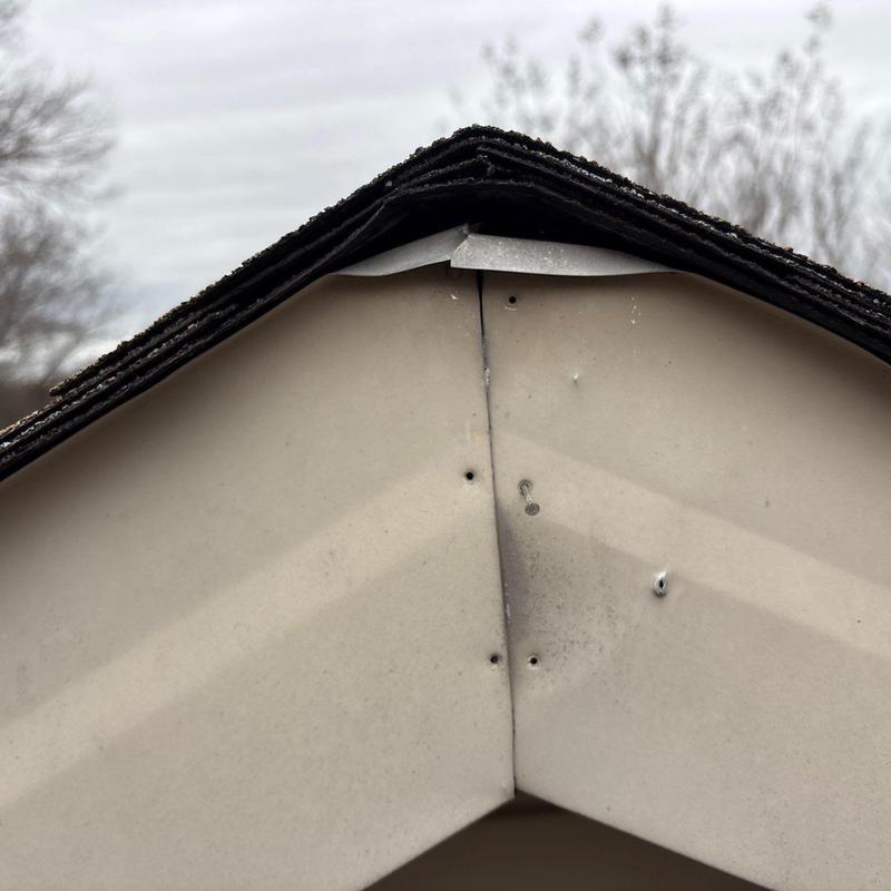 Ridge vent with hail damage and loose shingles