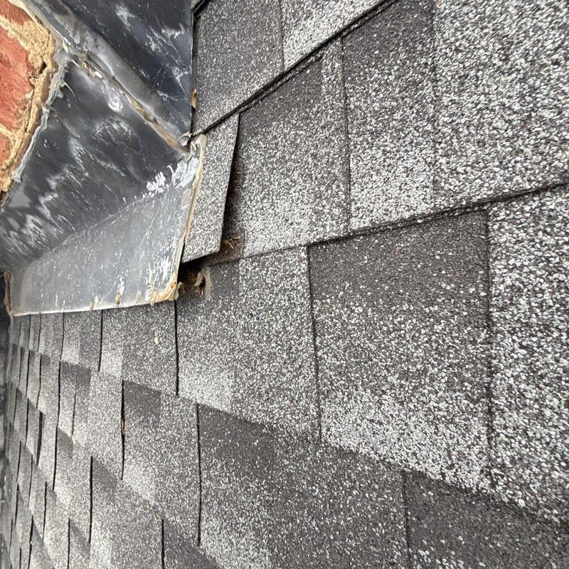 Asphalt shingles near metal flashing with hail damage