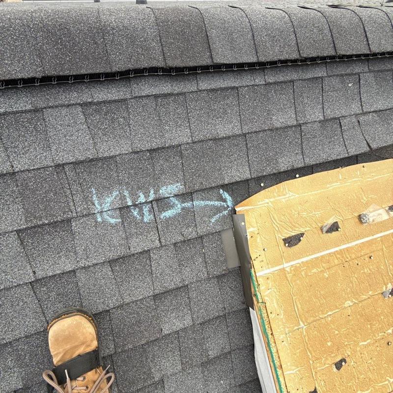 Asphalt shingles with chalk-marked hail damage near flashing