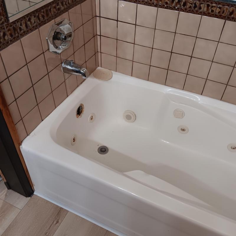 Bathtub drain and jet cleaning in tiled bathroom