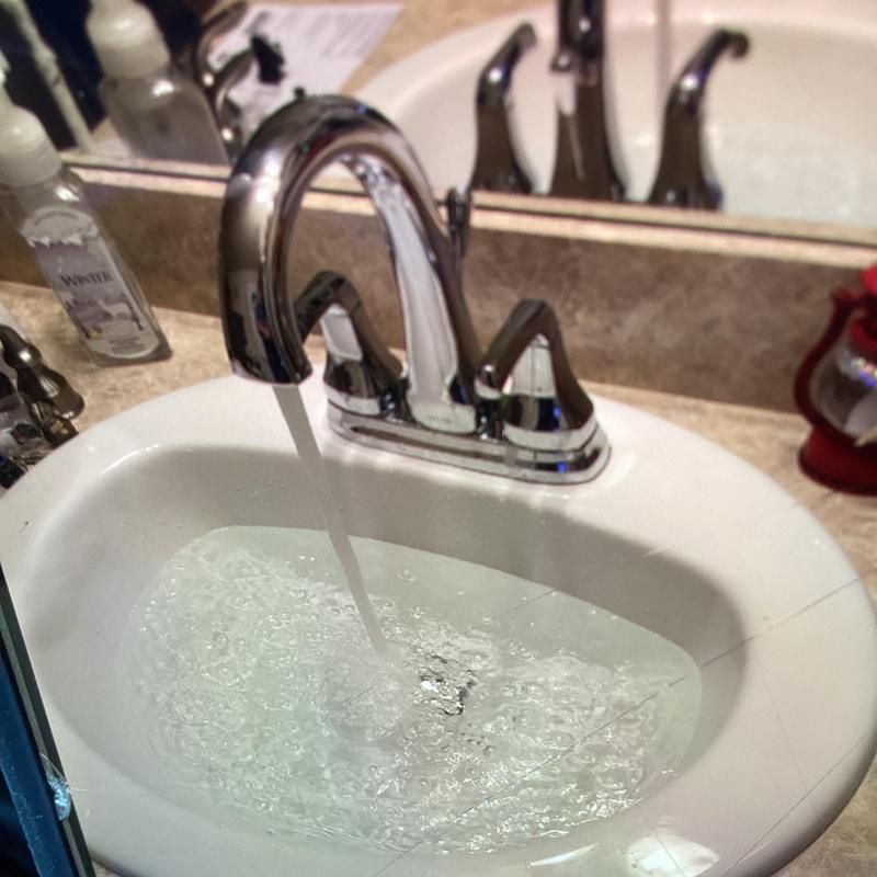 Vanity faucet with flowing water in bathroom sink