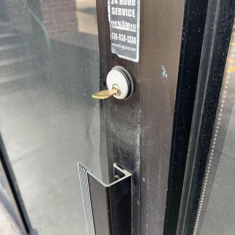 Mortise cylinder lock on glass door with key inserted