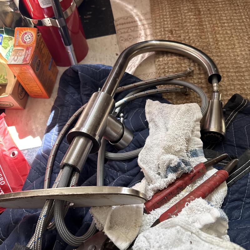 Kitchen faucet with supply lines and tools on blanket