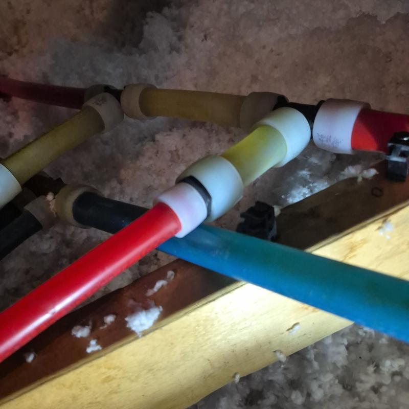 Red PEX pipe with fittings in attic insulation