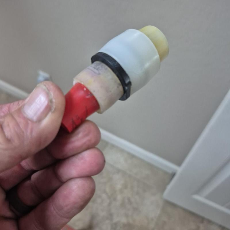 12 red PEX pipe fitting held by hand in interior space