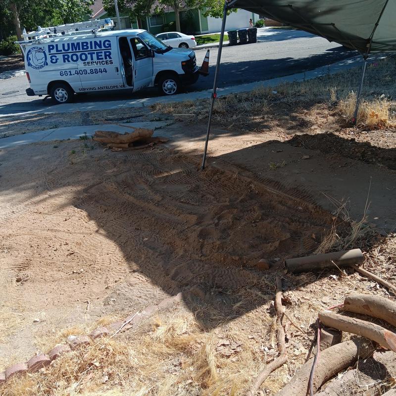 Broken sewer line excavation with roots and plumbing van